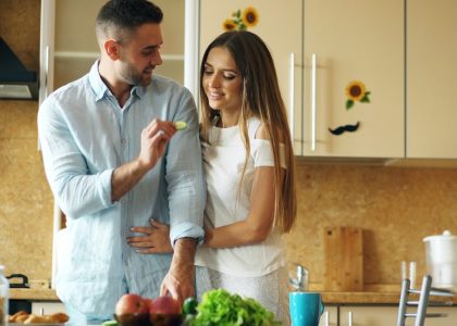 Happy young couple in the kitchen. Handsome man meet and feed his girlfriend early morning at home