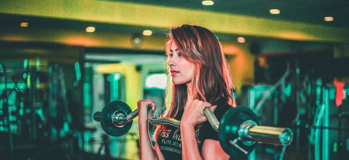 woman lifting black and gray barbell
